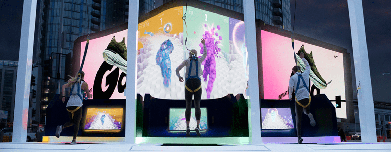 Three participants wearing harnesses on custom treadmills, with colourful avatars on the large screens in front of them.