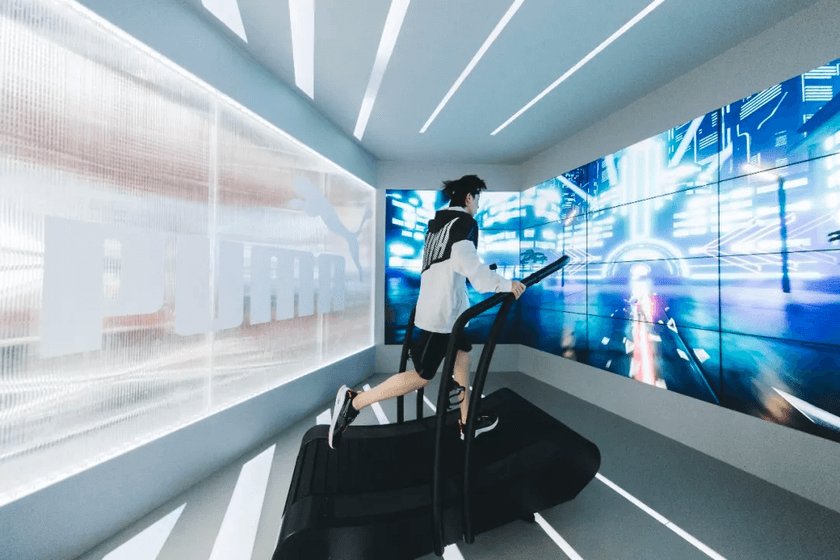 A runner on the PUMA treadmill facing the immersive wraparound game screens.